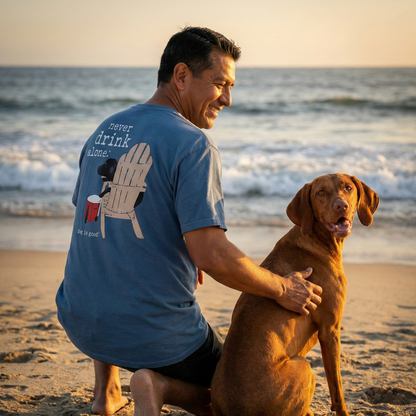 Man kneels on the beach with a dog, enjoying the sunset and a relaxed moment together.